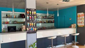 A bar area with a counter, stools, and a variety of bottles and glasses.