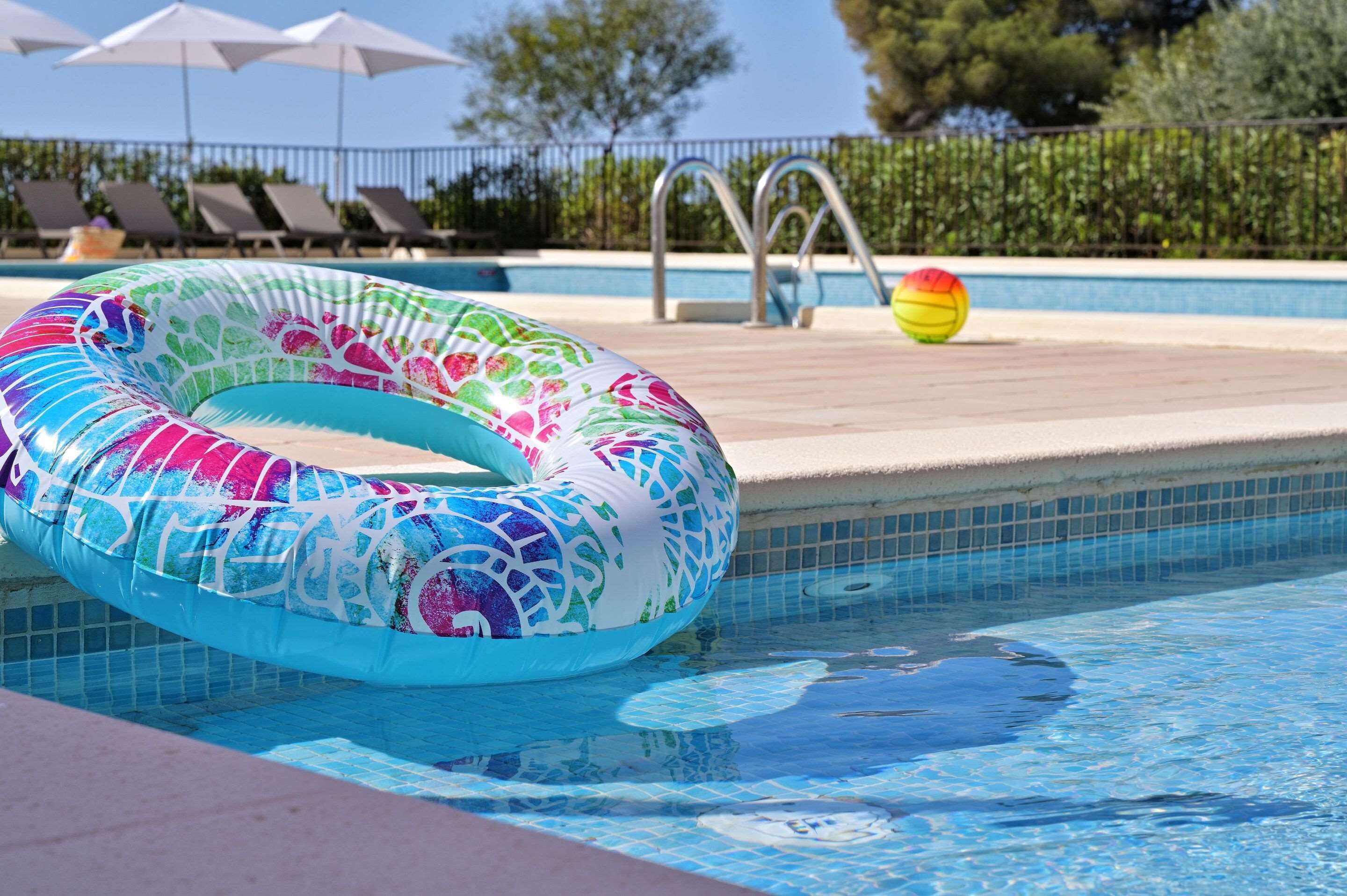 Ein Schwimmbecken mit einem bunten Schwimmreifen, einer Leiter und einem Strandball.