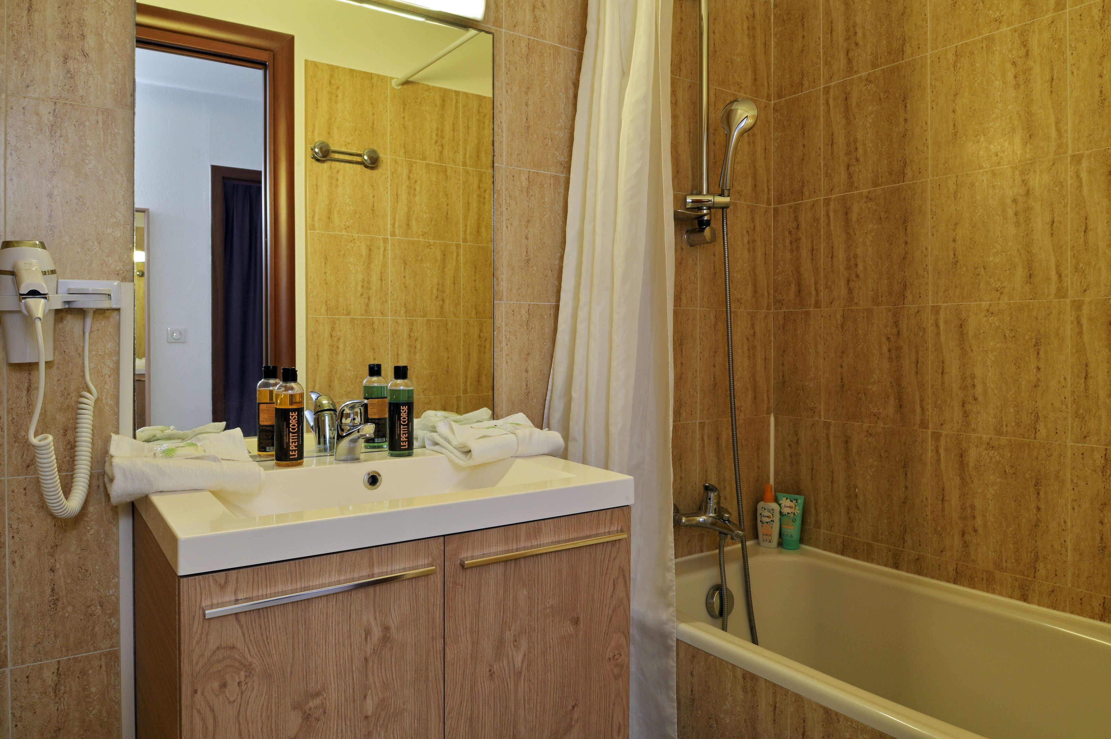 A bathroom with a wooden vanity, a mirror, a sink, and a bathtub.