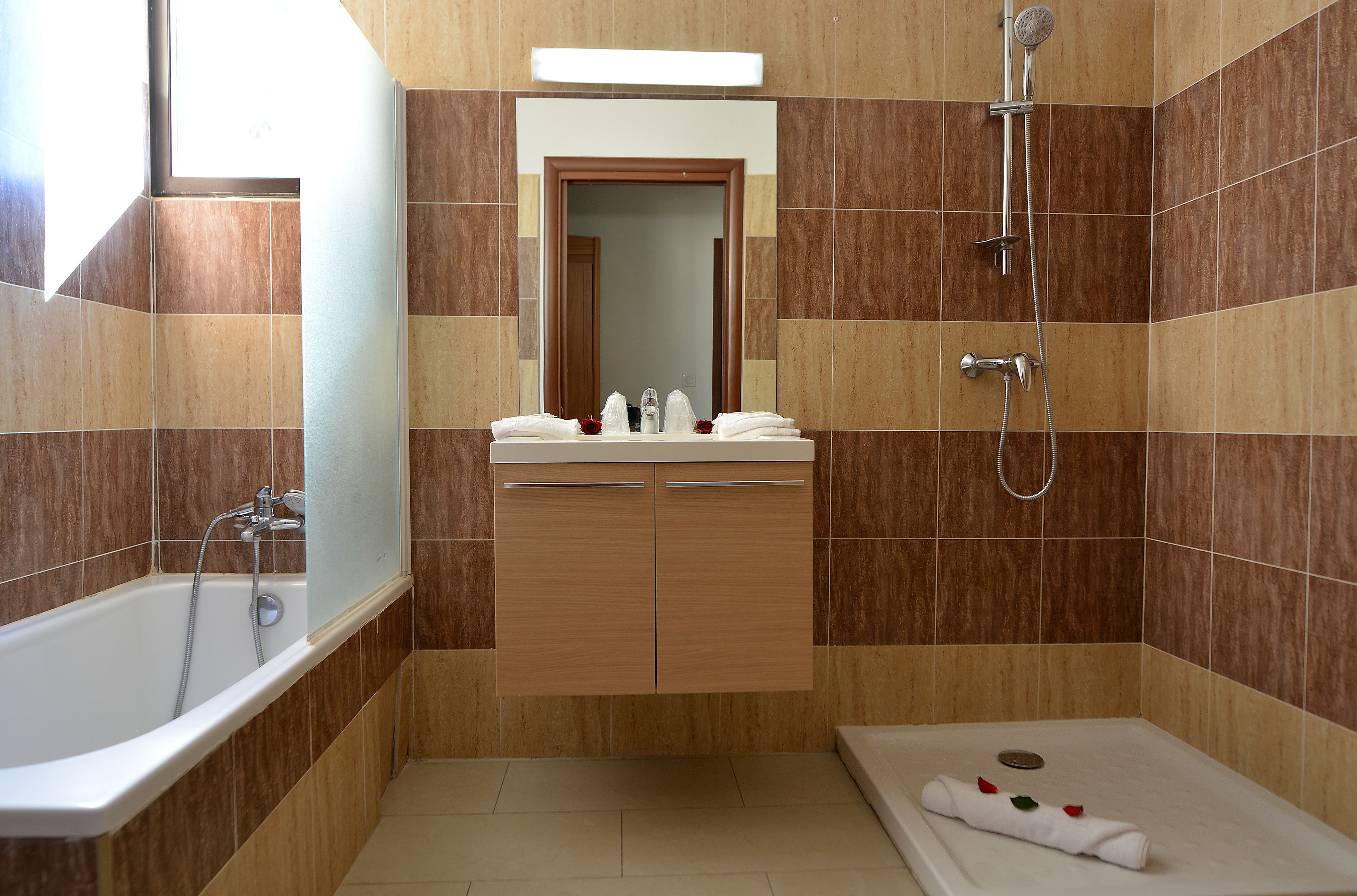 A modern bathroom with a bathtub, shower, vanity with a mirror, and a towel rack.