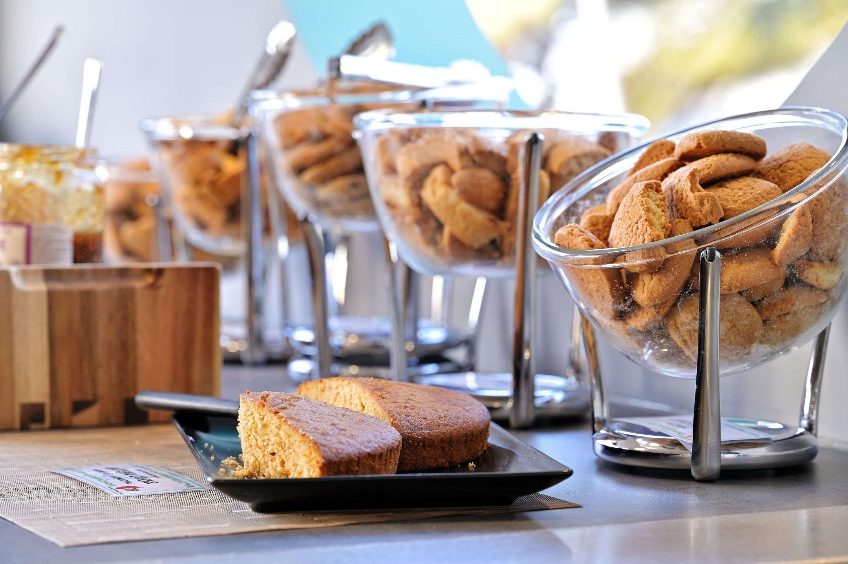 Un buffet proposant une variété de produits de boulangerie présentés dans des bols transparents, ainsi qu’une assiette avec des parts de gâteau.