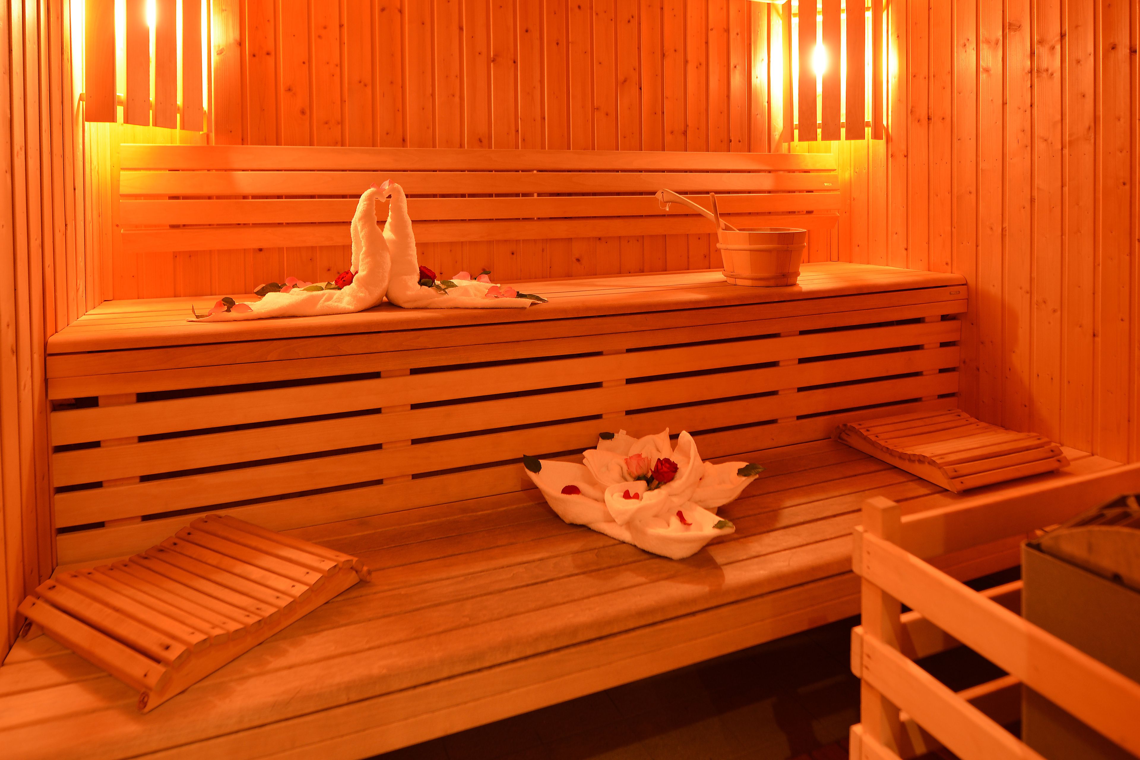 Een houten sauna bank met een handdoek en bloemen.
