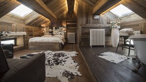 Un dormitorio rústico en el ático con vigas de madera, una cama, un sofá y un tragaluz.