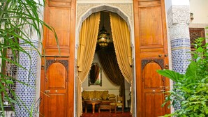 An open wooden door with a yellow curtain, leading to a room with a sofa and a table.
