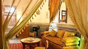 A traditional Moroccan room with a sofa, a small table, and a chair.