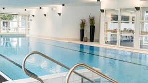 An indoor swimming pool with clear water, metal handrails, and a tiled floor. - Fuglsangcentret (Fredericia)