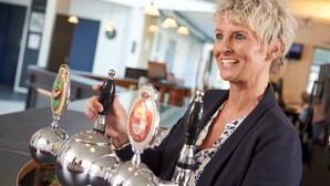 A person operating a tap with a beer tap in a well-lit indoor setting. - Fuglsangcentret (Fredericia)