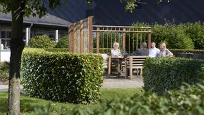 A garden patio with a wooden pergola, a table, and chairs. - Fuglsangcentret (Fredericia)