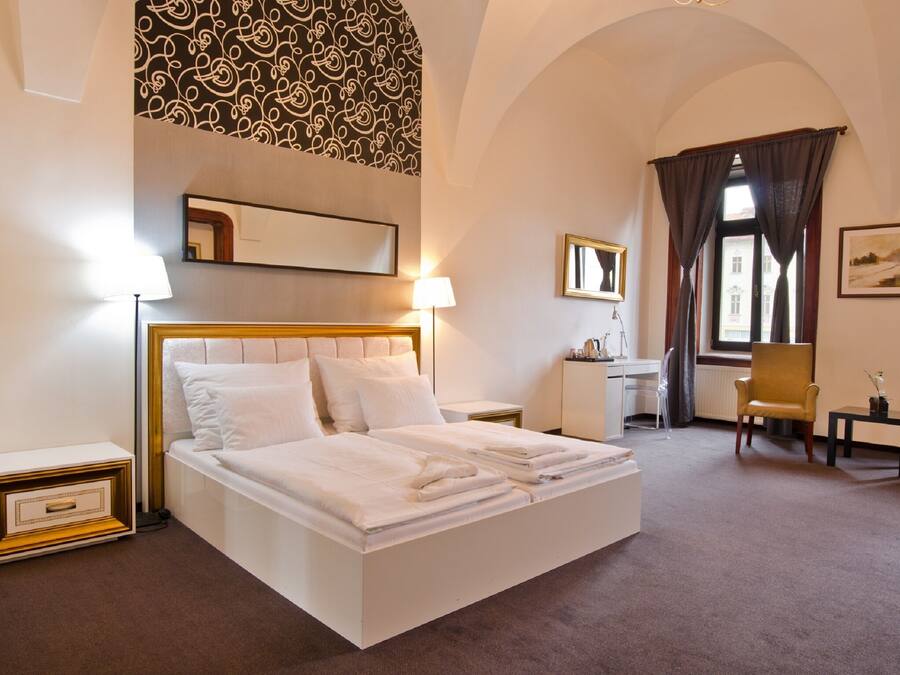 Une chambre d’hôtel avec un lit, un bureau, une chaise et une grande fenêtre avec des rideaux.