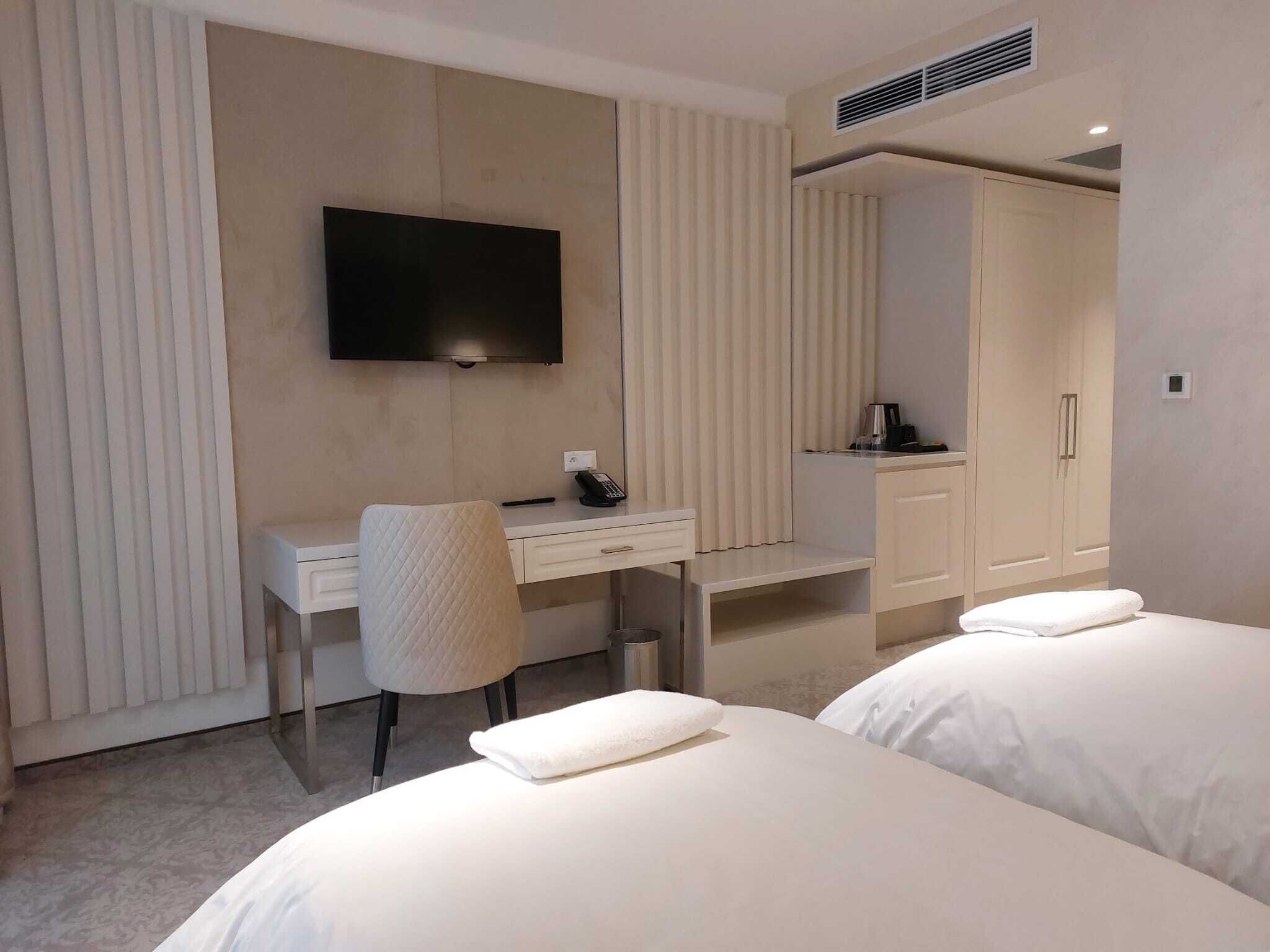 Une chambre d’hôtel comprenant un lit, un bureau avec une chaise, une télévision et une armoire.