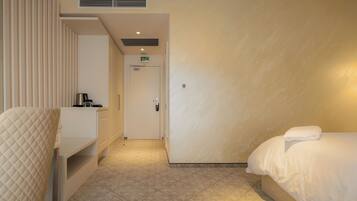 A hotel room with a bed, a bedside table, a chair, and a door leading to the bathroom.
