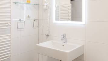 A modern bathroom with a white sink, a mirror, a shower, and a bathtub.