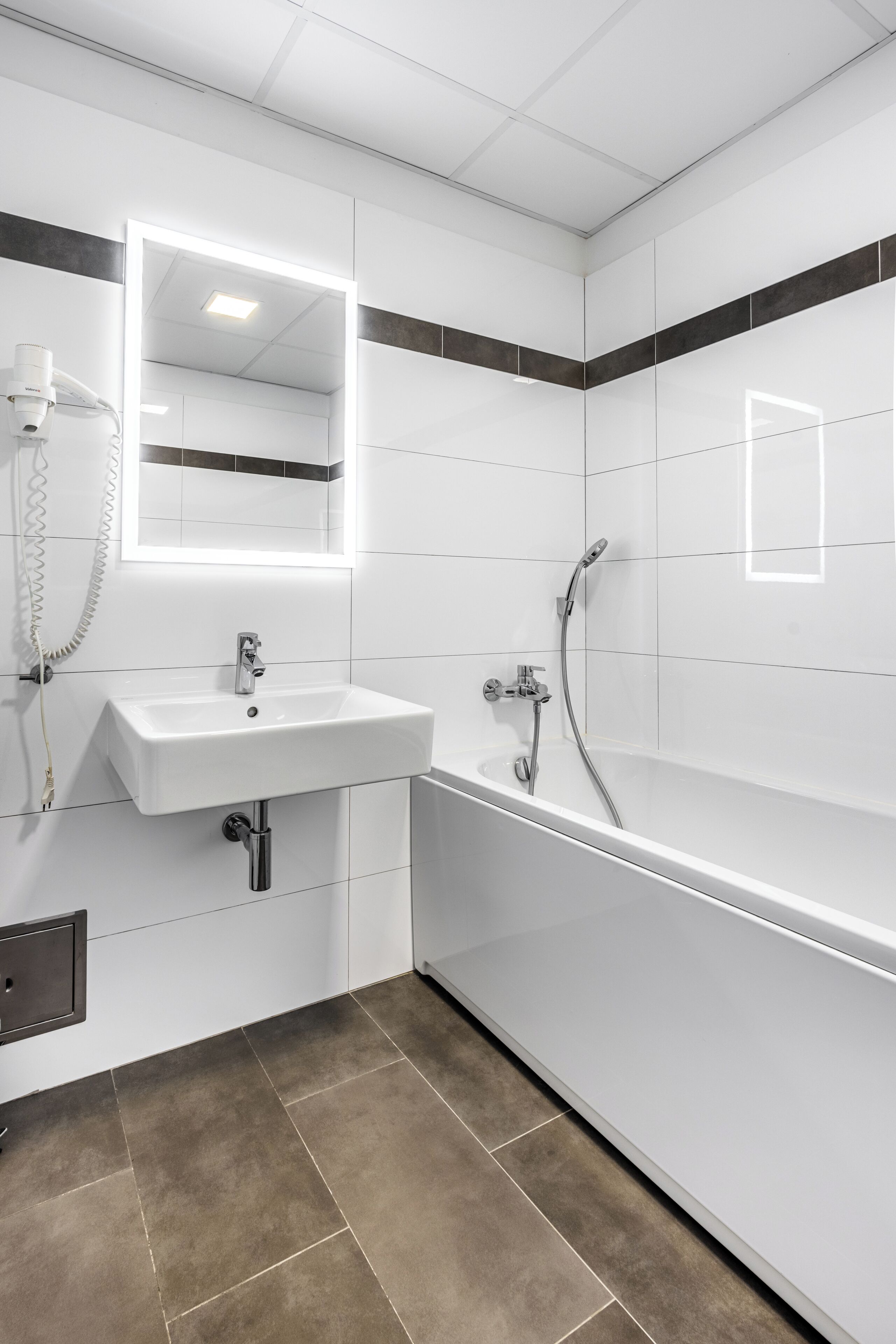 Ein modernes Badezimmer mit einem weißen Waschbecken, einem Spiegel und einer Dusche.