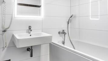 Ein modernes Badezimmer mit einem weißen Waschbecken, einem Spiegel und einer Dusche.