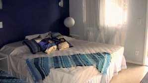 A bedroom with a bed, a bedside table, and a window with curtains. - Pousada Elementos (Buzios)