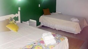 A room with two single beds, each with a white bedspread and a pillow. The walls are painted green, and there is a small painting on the wall. - Pousada Elementos (Buzios)