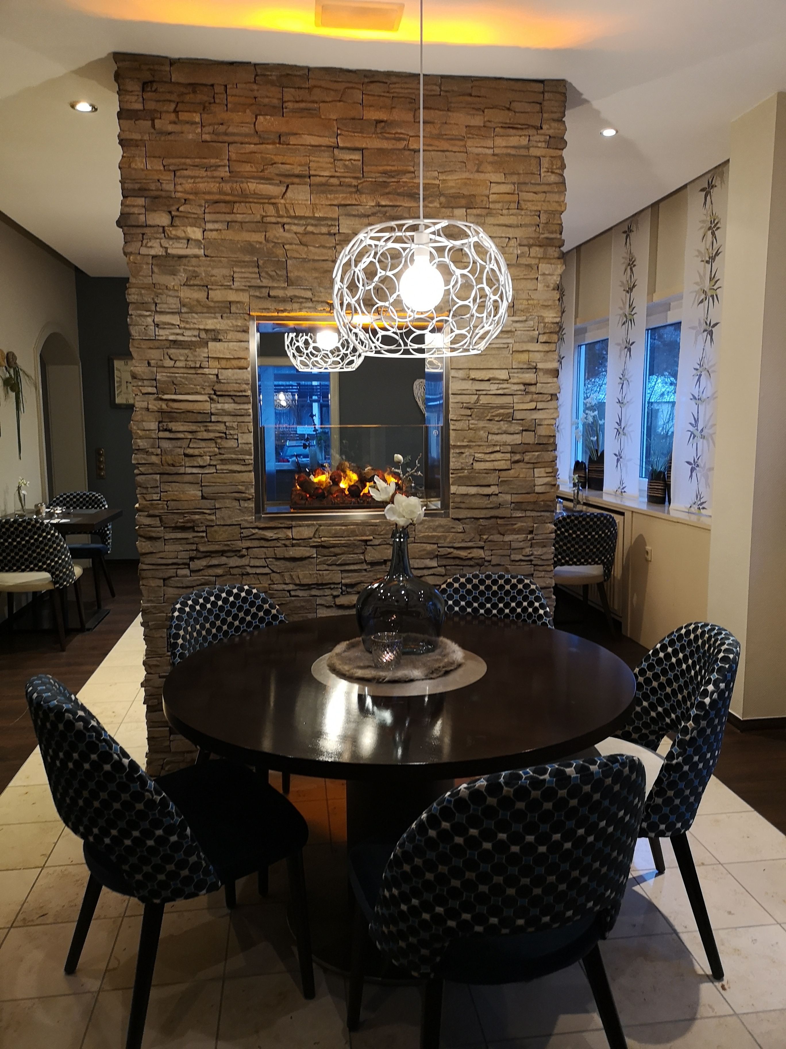 Un comedor con pared de acento de piedra, una mesa redonda y sillas estampadas.
