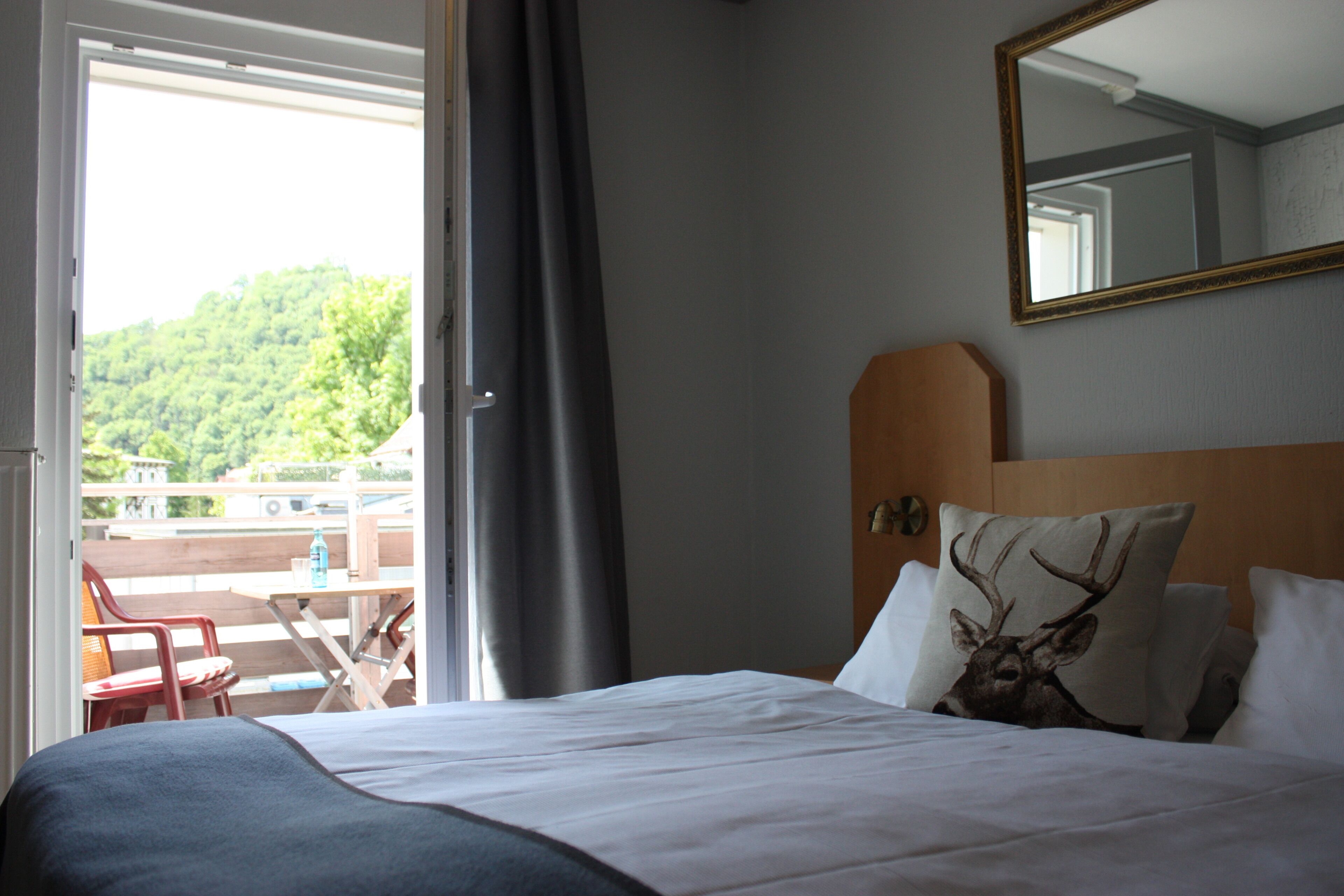 A hotel room with a bed, a large mirror, a view of a balcony, and a wooden headboard.