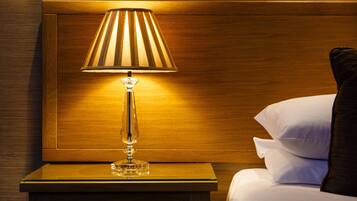 A wooden headboard with a bedside lamp and a bed with white linens.