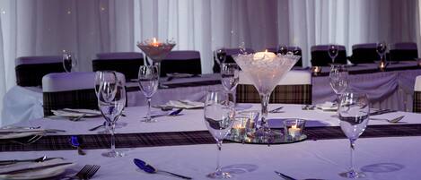 Una mesa dispuesta para una cena elegante, con copas de vino, cubiertos y velas.