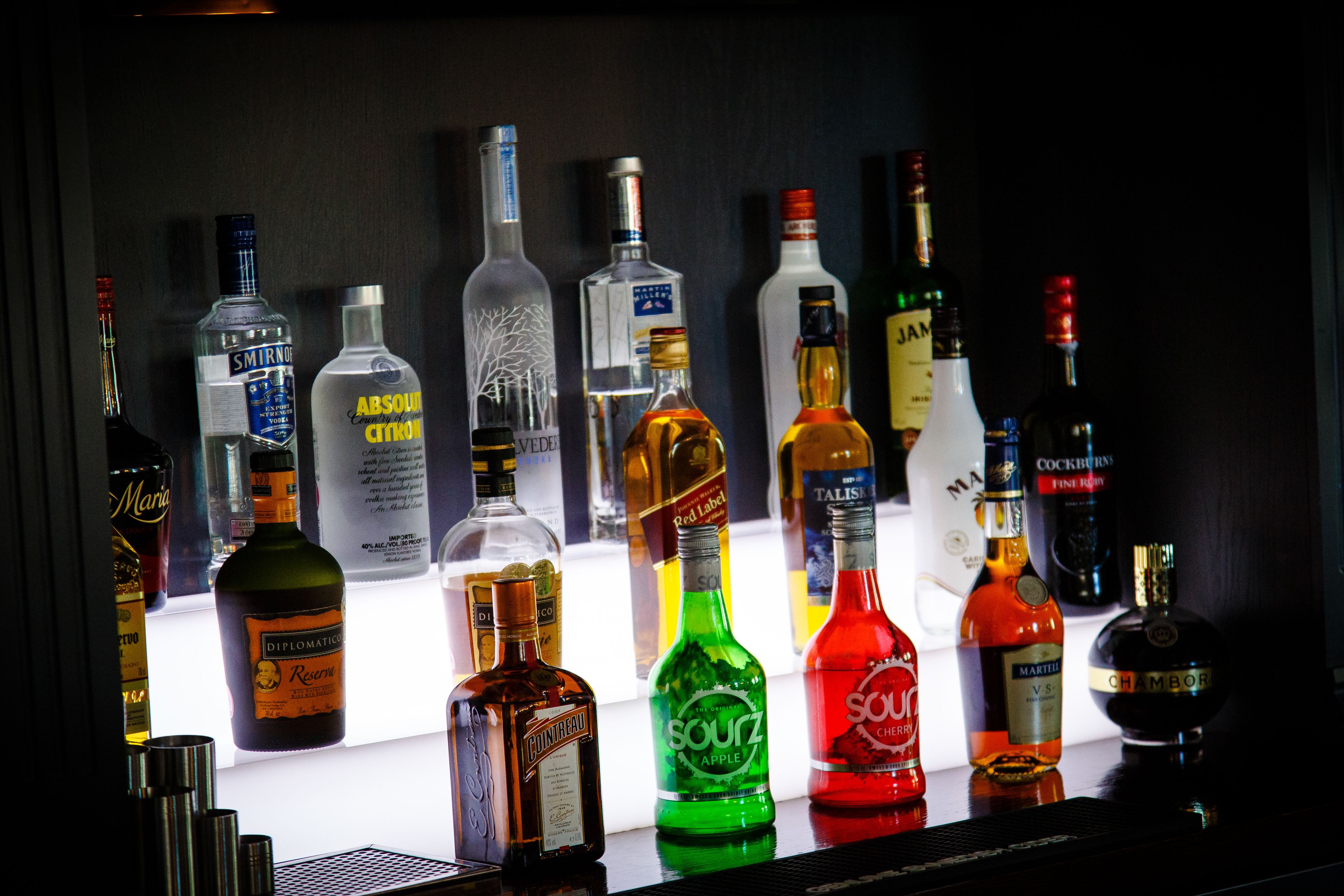 A variety of liquor bottles displayed on a bar counter.