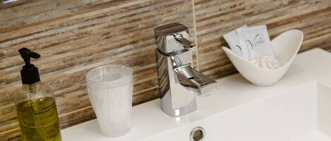 A bathroom sink with a soap dispenser, a glass, and a soap dish.