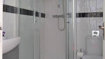 Un baño moderno con ducha de vidrio, lavamanos blanco y retrete.