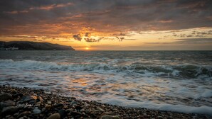 A beach with waves and a sunset. - The View Guest House (Llandudno)