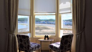 A bay window with two chairs and binoculars, overlooking a beach and buildings. - The View Guest House (Llandudno)