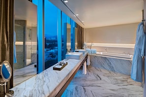 Enjoy a luxurious bathroom experience with a sink, large mirror, and city views.