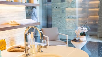 Sink, chair, and potted orchid adorn this bathroom, featuring a large oval sink and a mirror above.