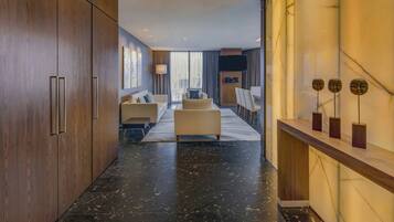 Un moderno vestíbulo de hotel con piso de mármol, un área de estar con sofás y sillones, un televisor de pantalla plana y un mostrador de recepción de madera.