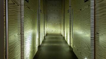 A narrow hallway with wooden paneling and illuminated signs indicating restrooms.