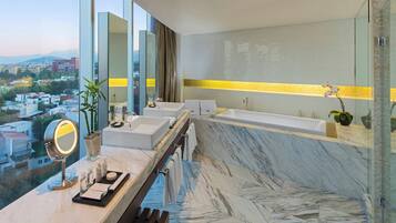 Casa de banho moderna com uma banheira grande, duas pias, toucador com espelho e vista para a cidade.