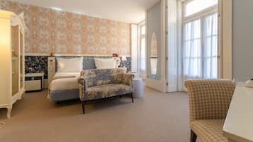 Une chambre à coucher comprenant un lit, un fauteuil à motifs floraux, une table de chevet et une armoire.