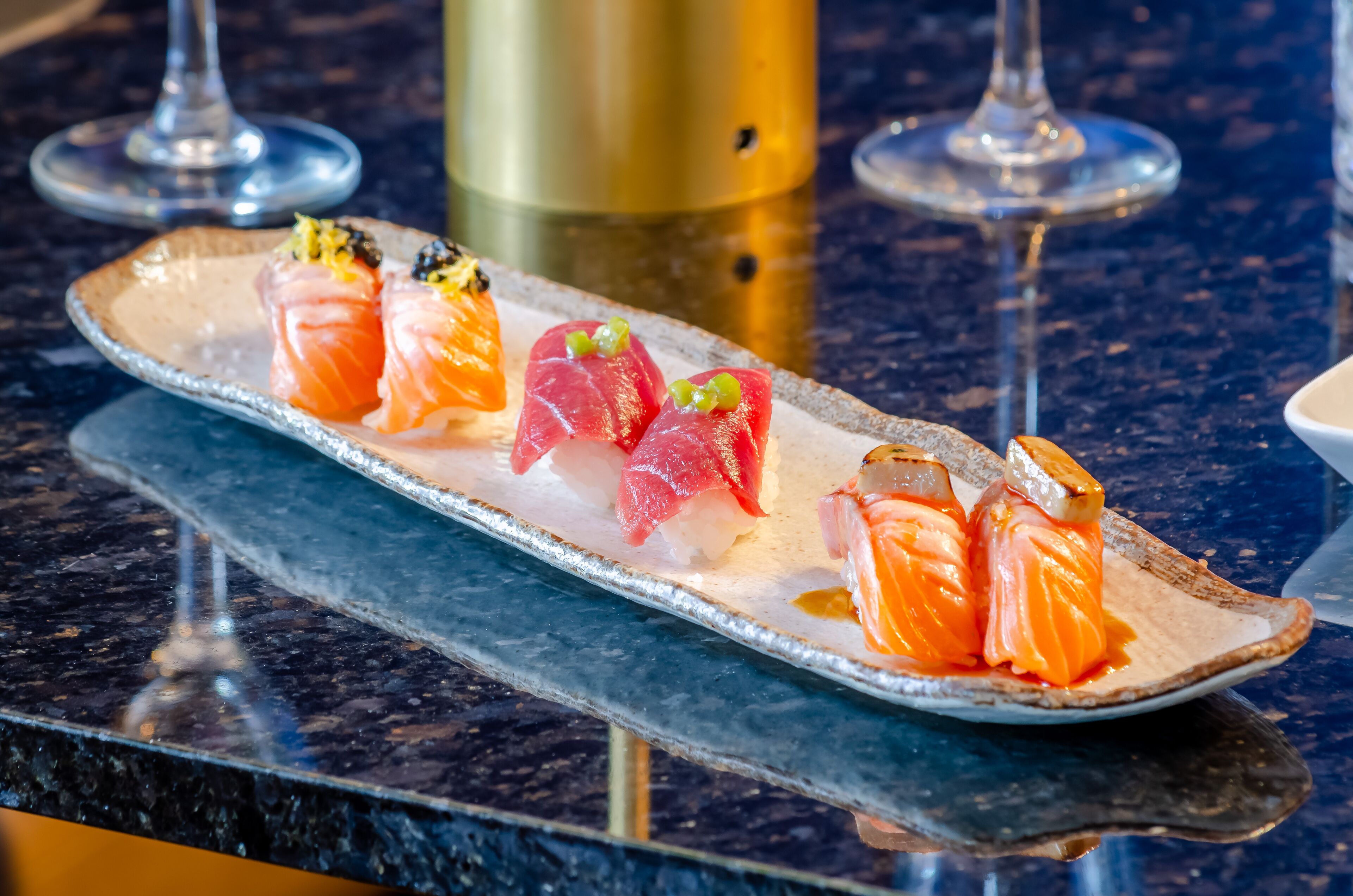 A sushi platter on a ceramic plate with a marble countertop.