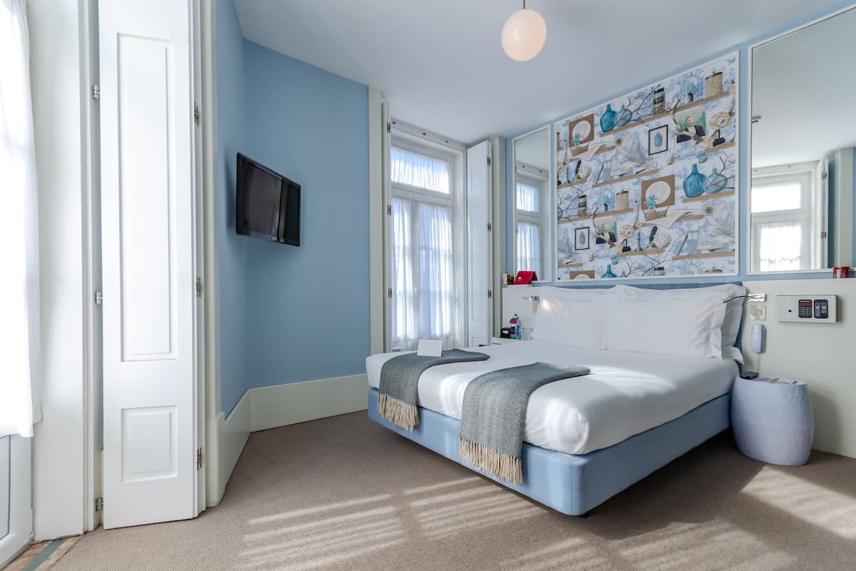 Een slaapkamer met een bed, een aan de muur bevestigde televisie en een grote spiegel.