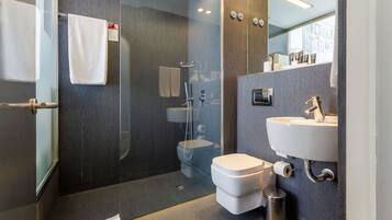 A modern bathroom with a glass-enclosed shower, a white toilet, and a sink with a mirror above it.