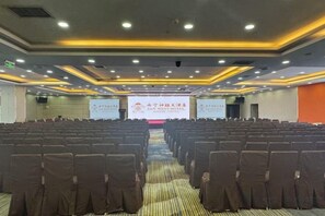 A conference room with rows of chairs, a podium, and a presentation screen. - San Want Hotel (Xining)