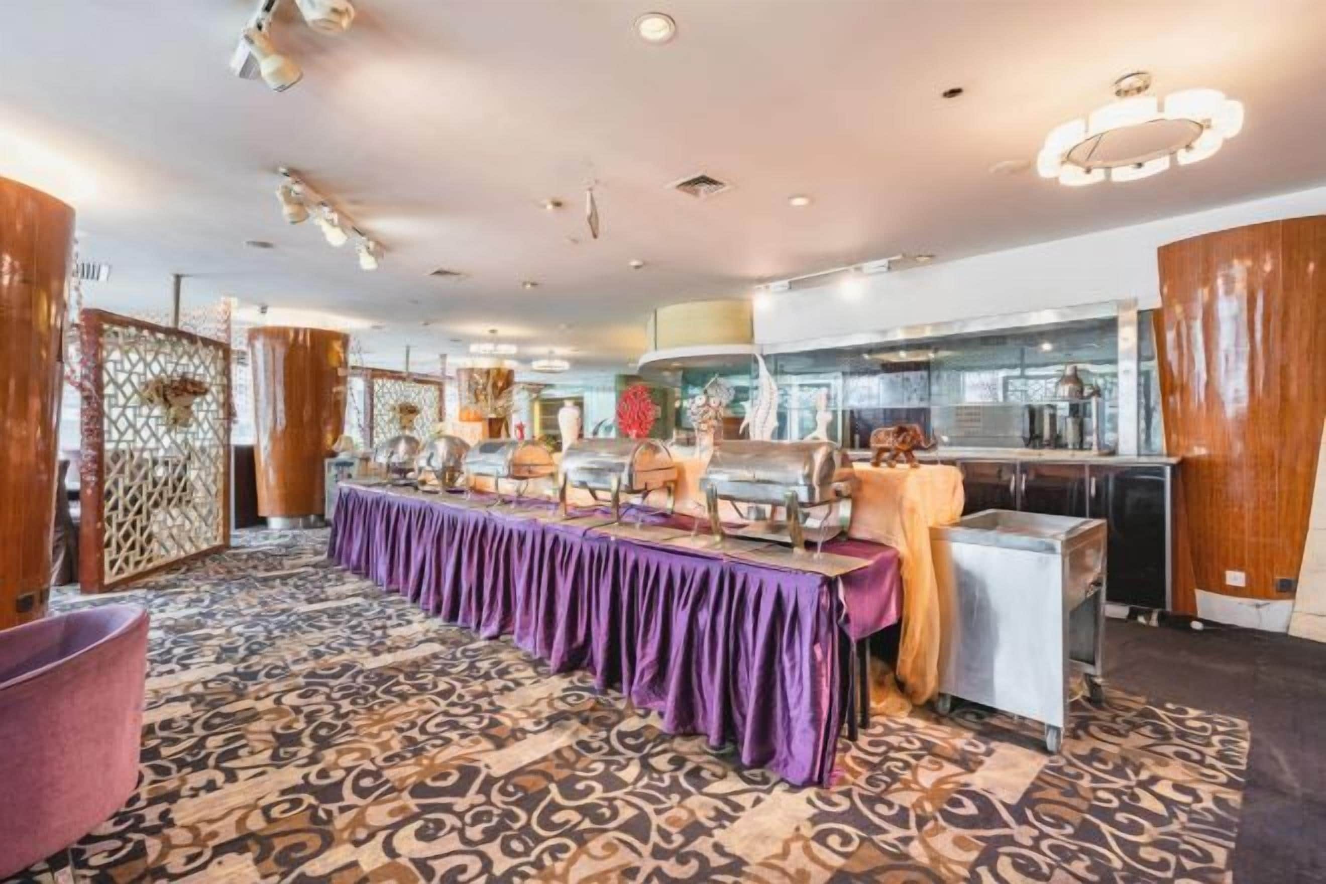 A hotel dining area with a long table, chairs, and a buffet setup.
