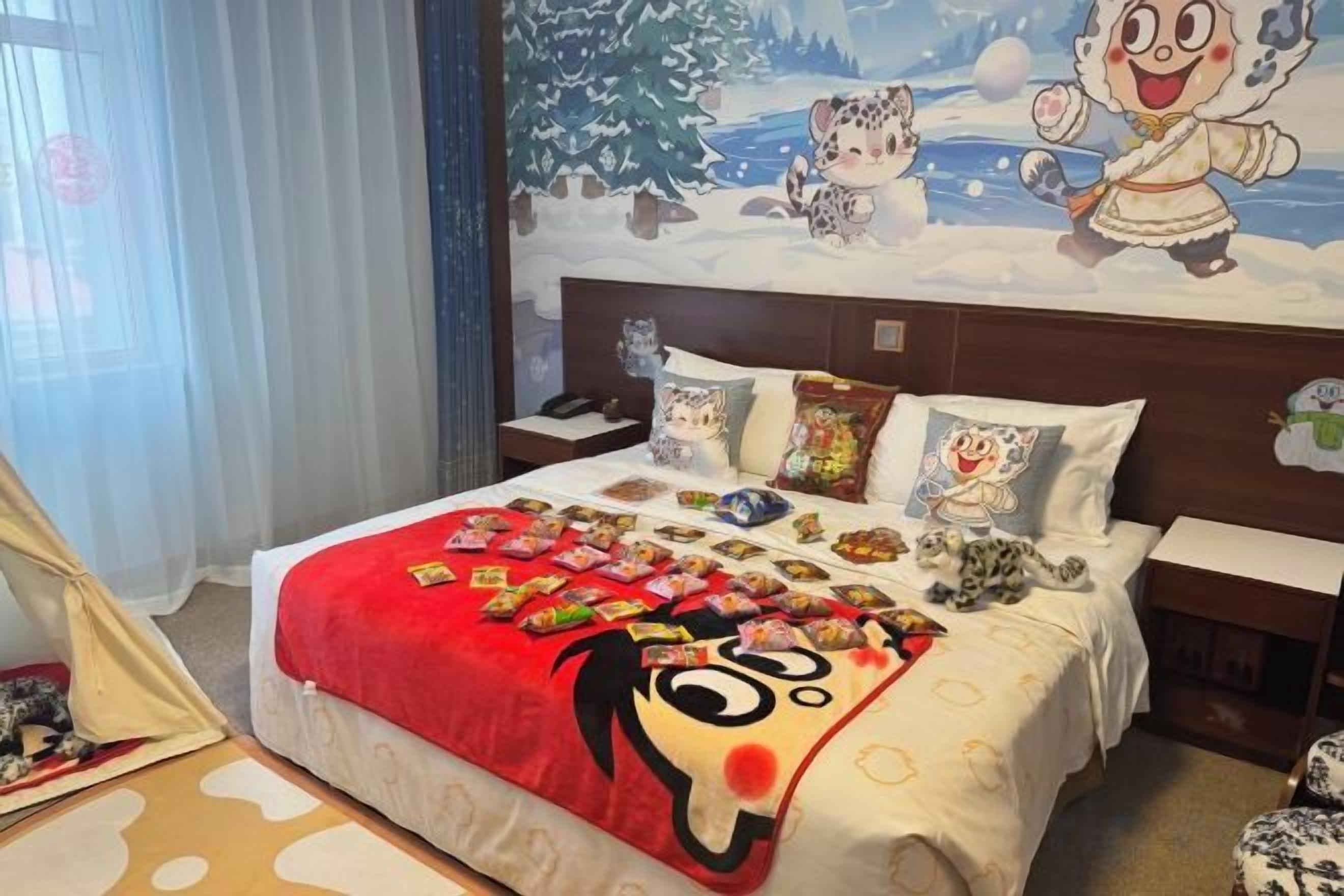 A hotel room with a bed, a nightstand, a tent, and a mural on the wall.