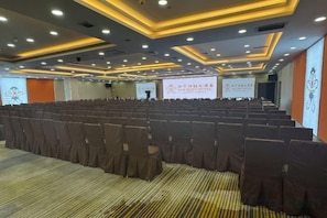 A conference room with rows of chairs, a projector screen, and a banner with text. - San Want Hotel (Xining)