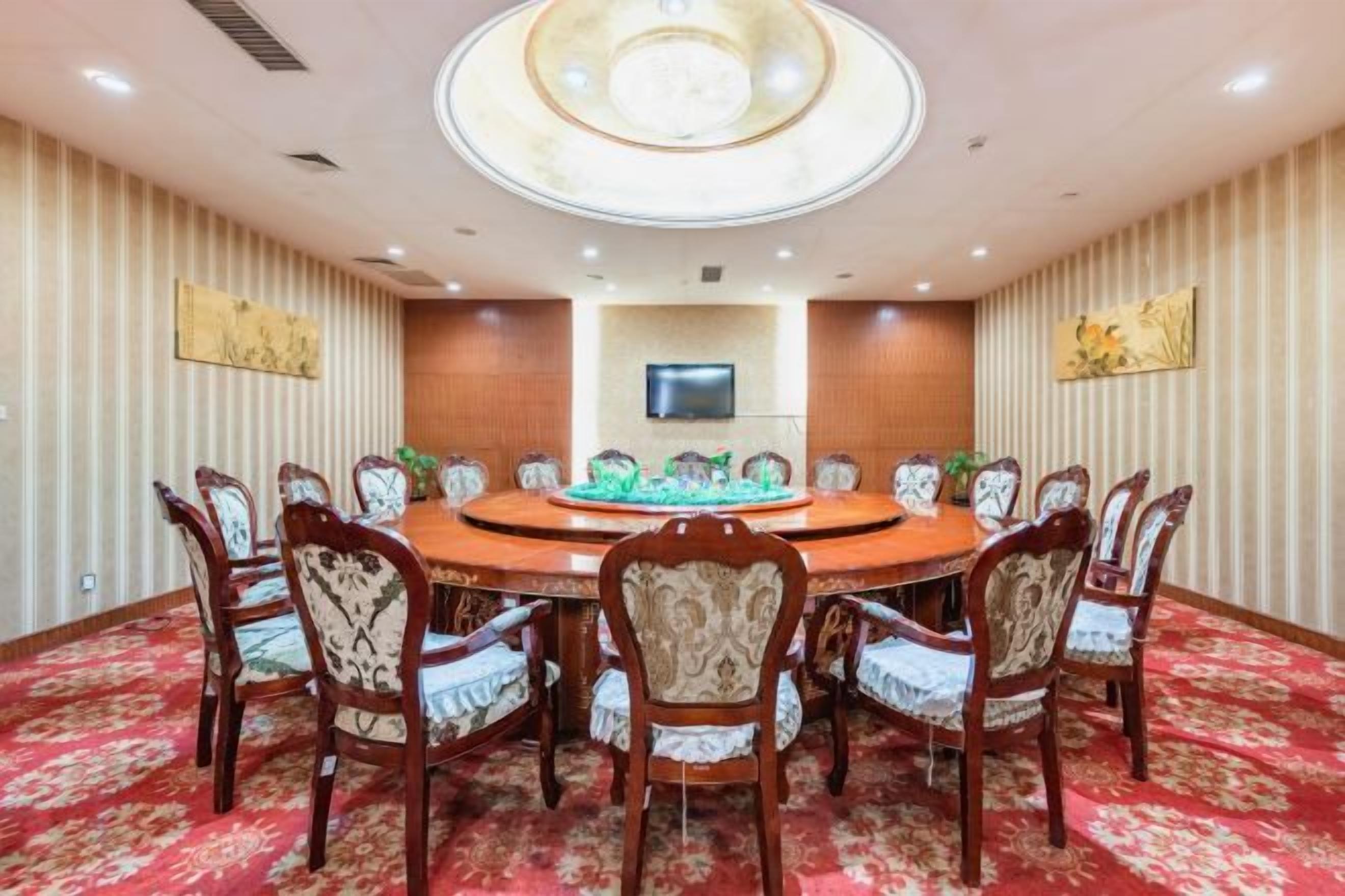 A conference room with a round table, chairs, a flat-screen TV, and decorative wall panels.
