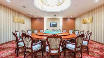 A conference room with a round table, chairs, a flat-screen TV, and decorative wall panels.