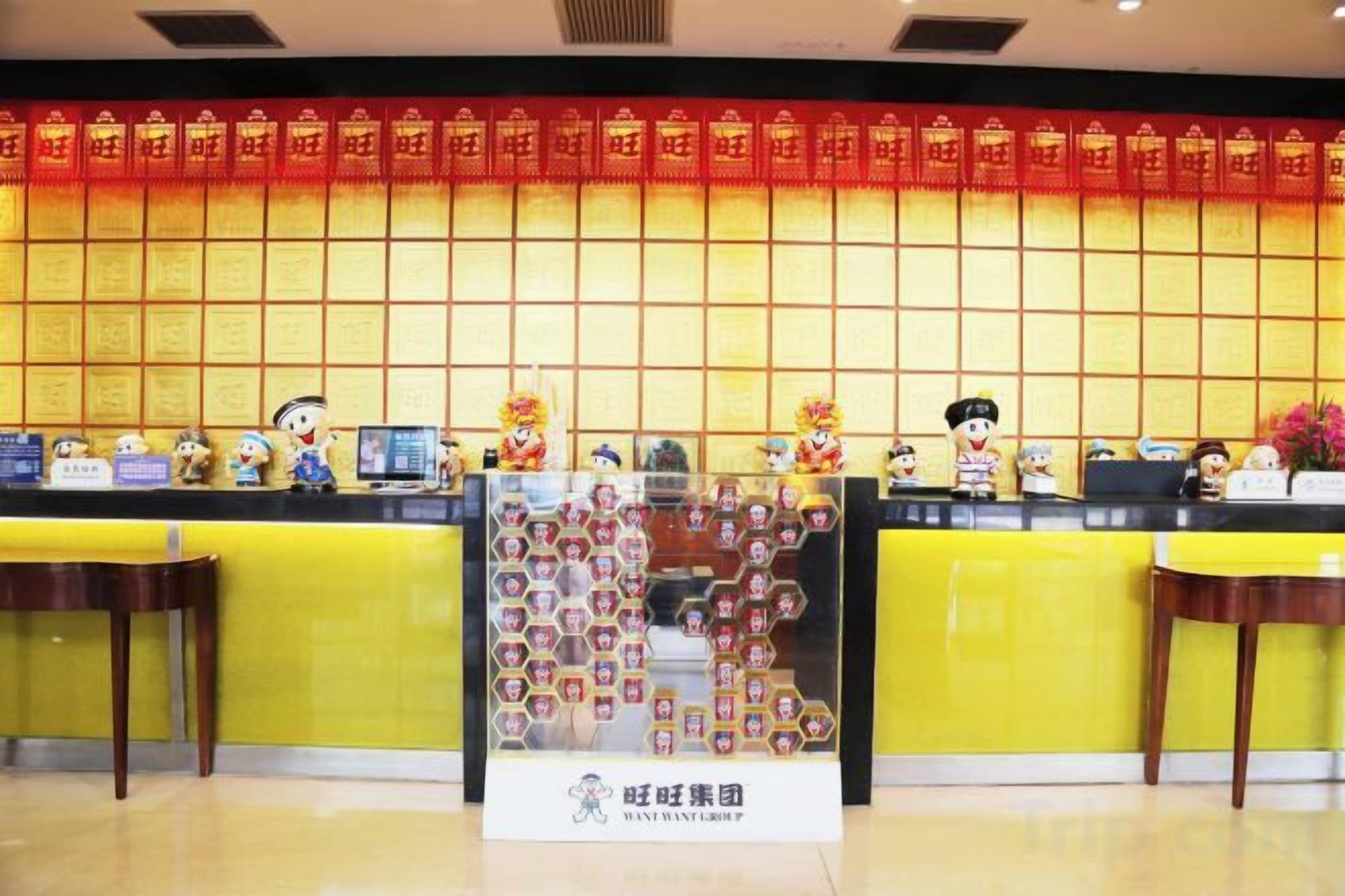 A reception desk with a red and gold decorative wall, a glass display case with items, and a sign with Chinese characters.