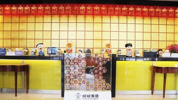 A reception desk with a red and gold decorative wall, a glass display case with items, and a sign with Chinese characters.