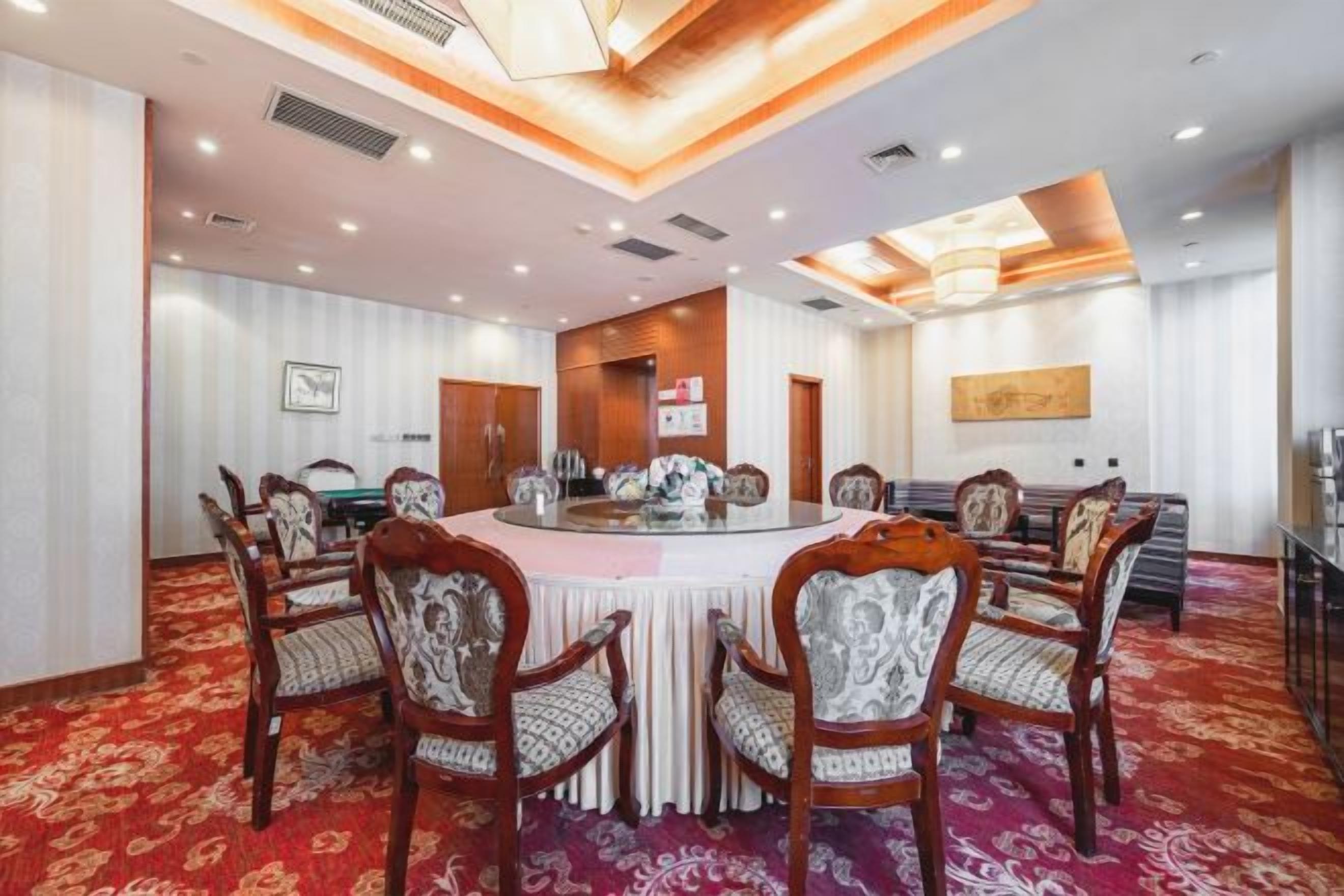 A conference room with a round table, chairs, and a carpeted floor.