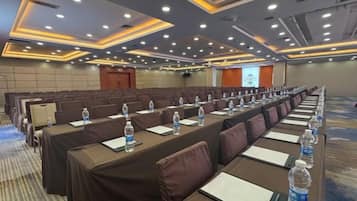 A conference room with rows of tables, each equipped with water bottles and notepads.
