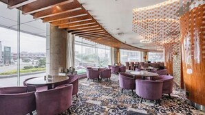 A modern restaurant with purple chairs and tables, large windows, and a patterned carpet. - San Want Hotel (Xining)