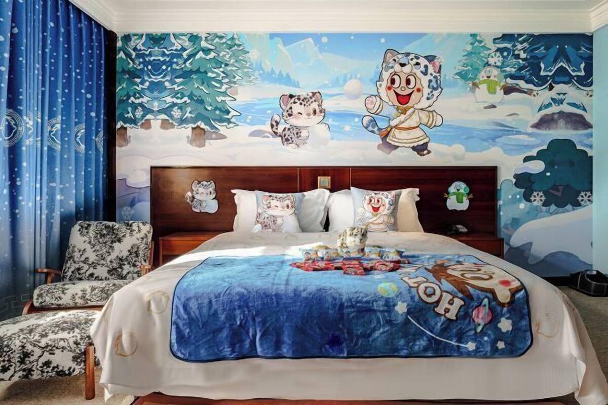 A bedroom with a bed, a chair, and a wall mural.